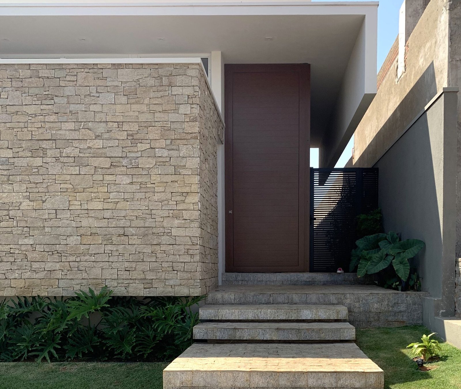 Casa AF — Adamantina: entrada com porta de madeira e revestimento em pedra — arquitetura residencial