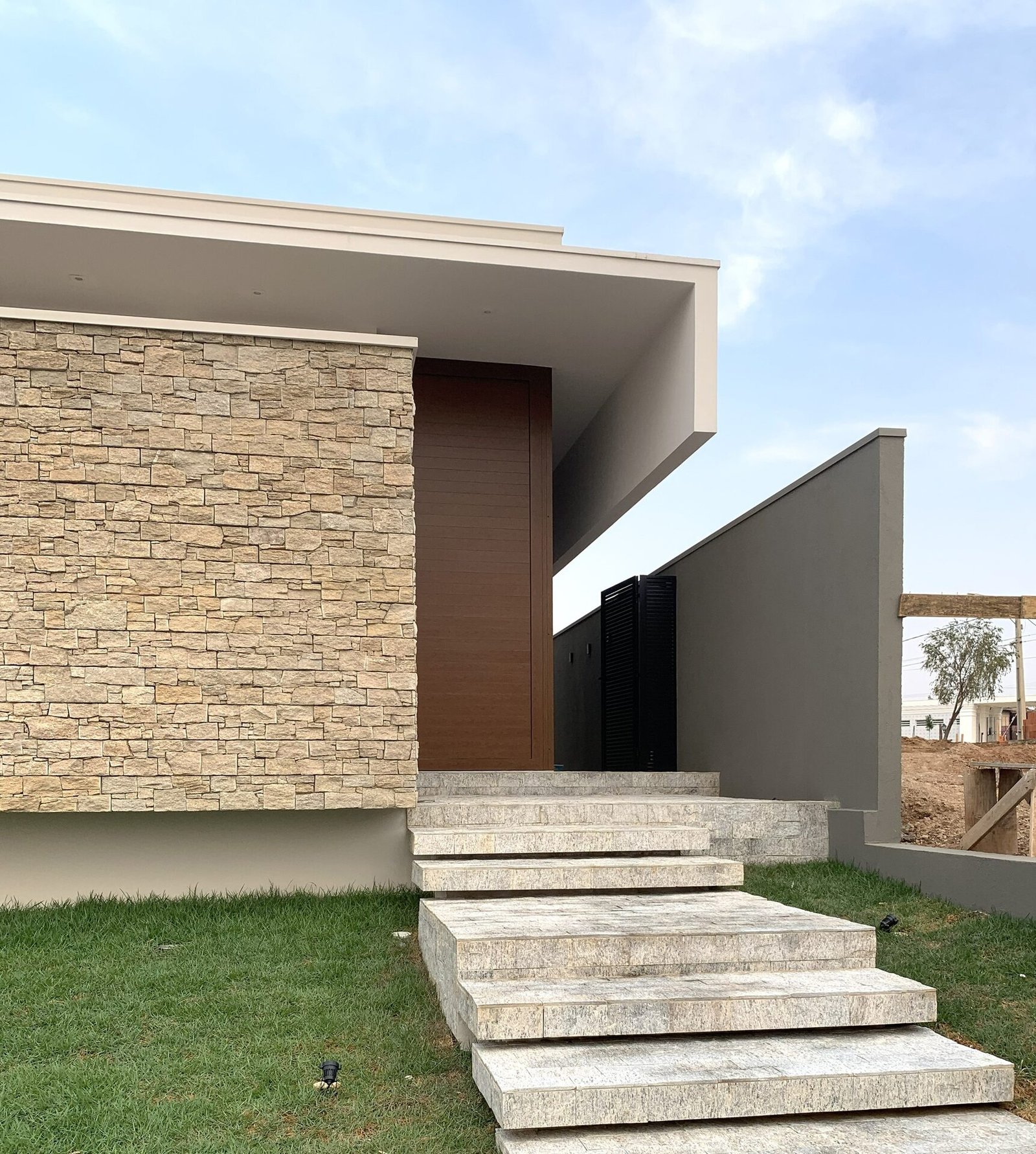 Casa AF — Adamantina: portão preto e fachada em pedra na entrada — arquitetura residencial
