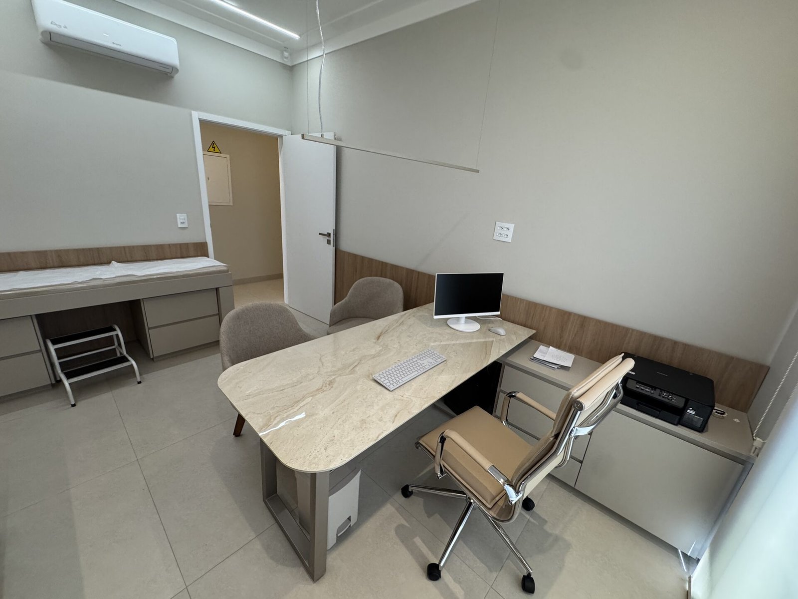 Clínica Integrata — Adamantina: consultório com mesa e maca ao fundo — projeto de arquitetura comercial