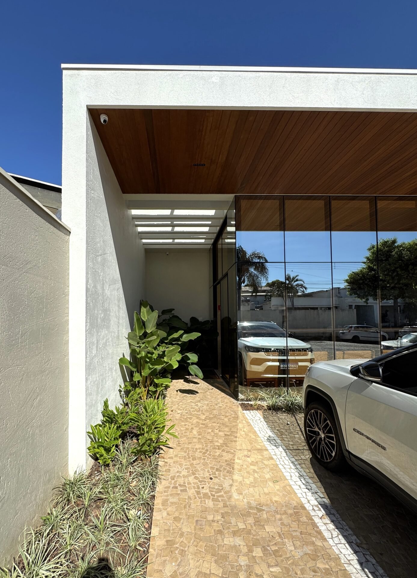 Clínica Integrata — Adamantina: passagem de entrada com paisagismo tropical — projeto de arquitetura comercial